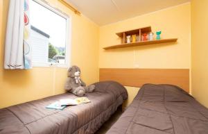a bedroom with two beds and a teddy bear sitting on the bed at ZEcamping 4 étoiles familial - parc aqua et soirées animées in Murol