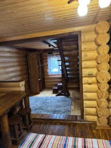 a log cabin with a tree in the middle of the room at Лісовий котедж in Synevyrsʼka Polyana