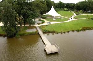 a bridge over a pond with a large white tent at ZEcamping 3 étoiles dog friendly bien-être piscine au bord dun lac in Loudéac +10 photos