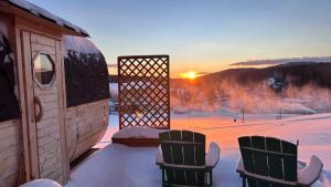 a couple of chairs sitting on a porch with the sunset at Aparthotel Teddy Kvilda in Kvilda