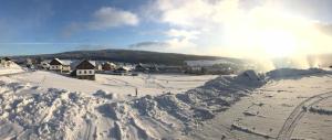a village covered in snow with the sun in the background at Aparthotel Teddy Kvilda in Kvilda