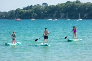 3 personnes sur des planches de paddle dans l'eau dans l'établissement Camping 4 étoiles - Piscine - eec0di, à Fouesnant