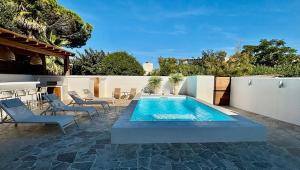 um pátio com uma piscina, cadeiras e uma cerca em Villa premium, tribu friendly, vaste patio & piscine em Mauguio