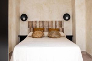 une chambre avec un grand lit blanc avec des oreillers marron dans l'établissement Lola3 Apartamento VUT, à Lucena