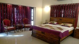Hotel Comfy Lodge في Dargai: غرفة نوم بسرير وكراسي وستائر