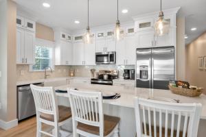 eine Küche mit weißen Schränken und eine Insel mit Stühlen in der Unterkunft 240 Olive Shell Court in Hilton Head Island