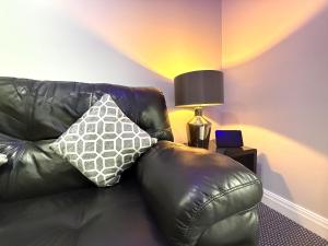 a black leather couch with a pillow on it at Maggie's Lodge in Leeds