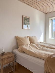 a white bedroom with a bed and a table at Gult Strandhus Med Udsigt Over Løkken in Løkken