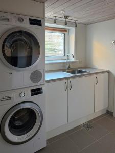 a kitchen with a washing machine and a sink at Gult Strandhus Med Udsigt Over Løkken in Løkken