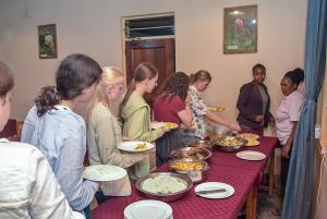 un gruppo di persone che si trovano intorno a un tavolo con cibo di Biez Homestay a Karatu