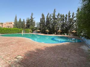 ein Pool in einem Resort mit Sonnenschirmen in der Unterkunft Charming Flat with AC Fast Wifi Secure Residence in Oulad Akkou