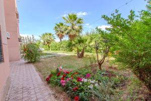einen Garten mit Blumen und Palmen und einen Gehweg in der Unterkunft Charming Flat with AC Fast Wifi Secure Residence in Oulad Akkou