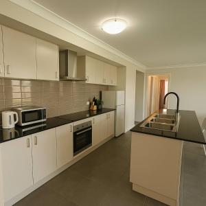 eine Küche mit weißen Schränken und schwarzen Arbeitsplatten in der Unterkunft Bright Family Retreat - Quiet Caboolture Stay in Caboolture