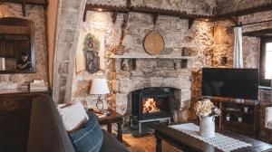 a living room with a stone wall with a fireplace at Agrovino Lofou in Lofou