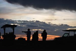 un gruppo di persone che si trovano davanti a un tramonto di Biez Homestay a Karatu