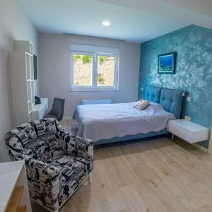 een slaapkamer met een bed, een bank en een stoel bij Apartamento Italia in Međugorje