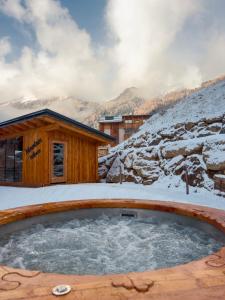 uma banheira de hidromassagem na neve em frente a uma cabina em Albergo Sporting em Peio Fonti