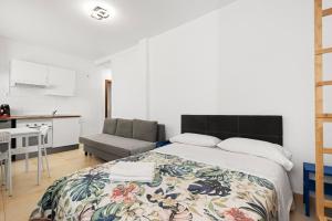 a bedroom with a large bed and a kitchen at Apartamentos Calle Nueva in Málaga