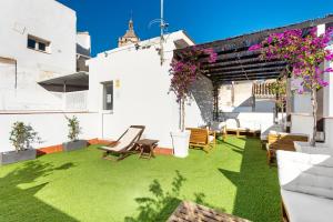 a patio with green grass and chairs on a building at Apartamentos Calle Nueva in Málaga