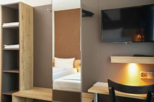 a room with a bed and a tv on a wall at Hotel Frohnhauser Hof in Essen