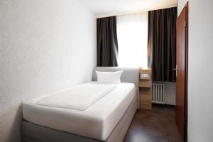 a white bed in a room with a window at Hotel Frohnhauser Hof in Essen +44 photos