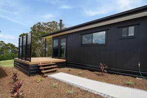 a black tiny house with a wooden deck at Grevillea Villa in Valdora