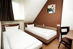 two beds in a room with a table and a chair at Hotel Frohnhauser Hof in Essen