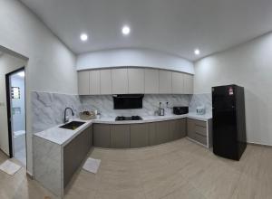 a kitchen with a black refrigerator and a sink at Hatasan Homestay Guess House in Perai