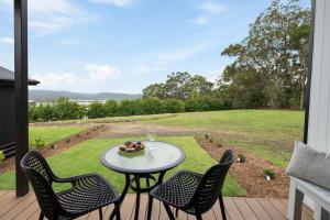 a table and chairs on a patio with a view of a field at Lemon Myrtle Villa in Valdora