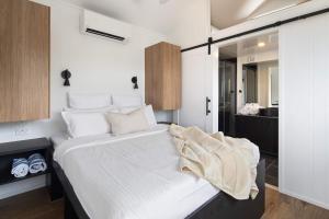 a bedroom with a large bed with white sheets at Lemon Myrtle Villa in Valdora +12 photos