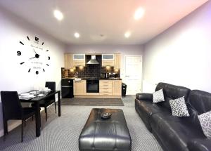 a living room with a couch and a table and a clock at Maggie's Lodge in Leeds