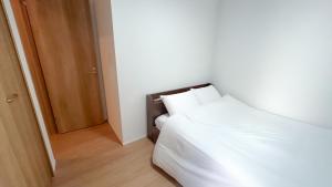 um quarto com uma cama branca e uma porta aberta em 福岡旅路 博多住吉包棟民宿 3號館 em Fukuoka