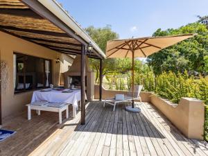 eine Holzterrasse mit Tisch und Sonnenschirm in der Unterkunft Howberry Hills in Plettenberg Bay + 6 Fotos