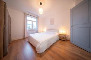 um quarto com uma grande cama branca e uma janela em appartement confortable à la frontière de bâle One 6 personnes em Saint-Louis