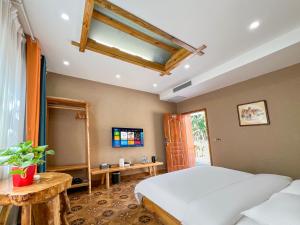 a bedroom with a white bed and a television at Turpan Grape Spring Inn in Turfan
