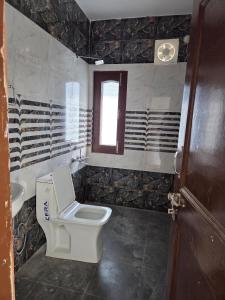 Un baño con inodoro, lavabo y ventana. en The Sunrise Retreat, en Solan