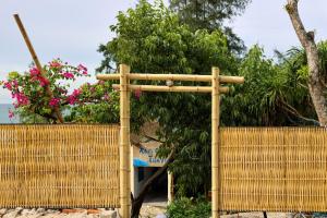 Una valla de bambú con una puerta con un árbol. en Xóm Chài Tân An, en Ấp An Lộc A