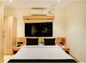 a bedroom with a large white bed and a window at Hotel O Malani Inn in Kukatpalli