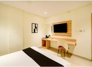 a hotel room with a bed and a desk with a television at Hotel O Malani Inn in Kukatpalli