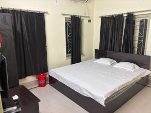 Un dormitorio con una cama grande con cortinas negras. en POP 84116K Hotel O Maa Tara Guest House, en Dum-Dum Junction