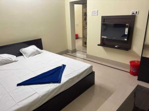 Un paraguas azul sobre una cama con un televisor de pantalla plana. en POP 84116K Hotel O Maa Tara Guest House, en Dum-Dum Junction 3 fotos más