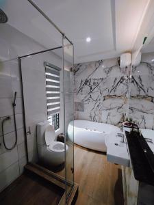 a bathroom with a glass shower and a sink and a toilet at Sahara Apartment Ikoyi in Lagos