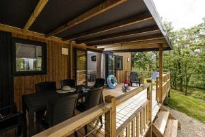 eine Holzterrasse mit einem Tisch und Stühlen darauf in der Unterkunft Chalet 4 étoiles - Piscine - ccafdif in Loupiac