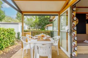 a patio with a white table and chairs at ZEcamping 3 étoiles familial animaux acceptés piscine couverte et chauffée in Saint-Hilaire-de-Talmont