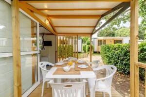 a patio with a white table and white chairs at ZEcamping 3 étoiles familial animaux acceptés piscine couverte et chauffée in Saint-Hilaire-de-Talmont
