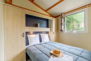 a bedroom with a bed with a hat on a table at ZEcamping 3 étoiles familial animaux acceptés piscine couverte et chauffée in Saint-Hilaire-de-Talmont +46 photos