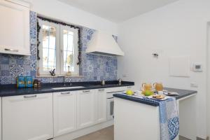 - une cuisine avec des placards blancs et du carrelage bleu et blanc dans l'établissement B&B Positano, à Giugliano in Campania
