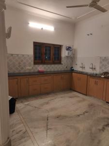 德拉敦Ashiana By Ijabojyu的空荡荡的厨房，配有木制橱柜和水泥地面。