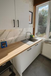 eine Küche mit weißen Schränken und einer Spüle und einem Fenster in der Unterkunft Maison cosy avec terrasse et jardin - Aéroport gare in Charleroi