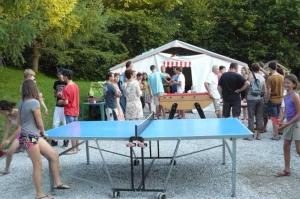 un groupe de personnes debout autour d'une table de ping-pong dans l'établissement Camping 3 étoiles - Piscine - ccbaddh, à Louvie Juzon